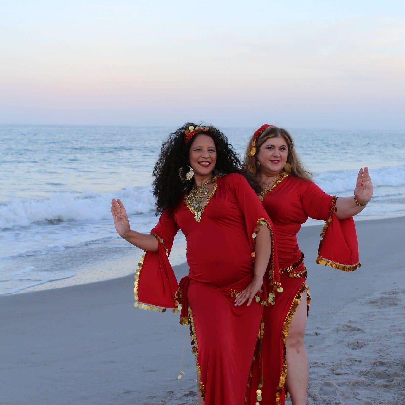 Two dancers in red on the beach at sunset