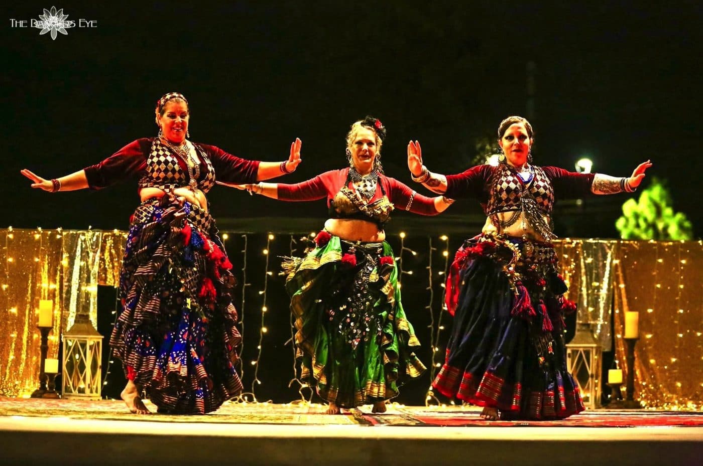 Three dancers performing on stage at the holiday hafla